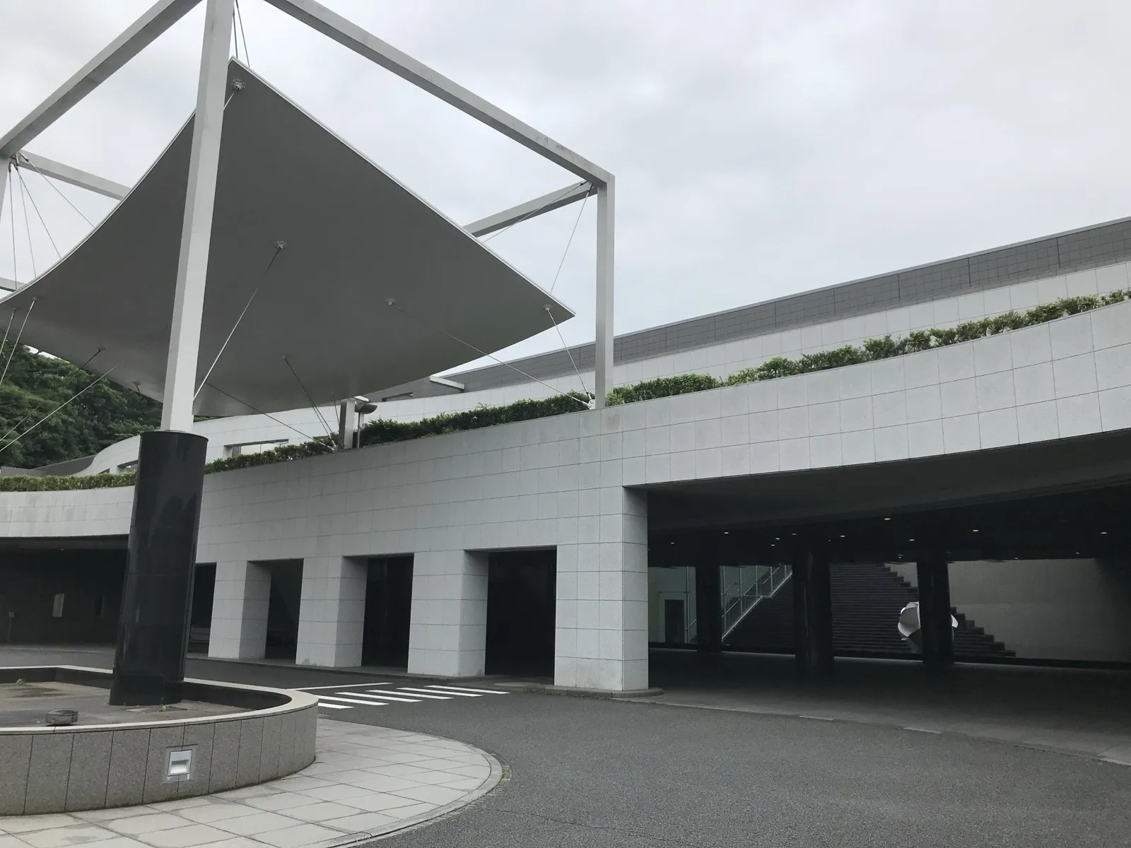 横浜市北部斎場の外観。白いタイル張りの建物と、大きな白い幕の屋根